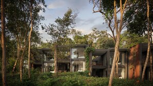 Un immeuble moderne à plusieurs étages, entouré d’une végétation luxuriante.