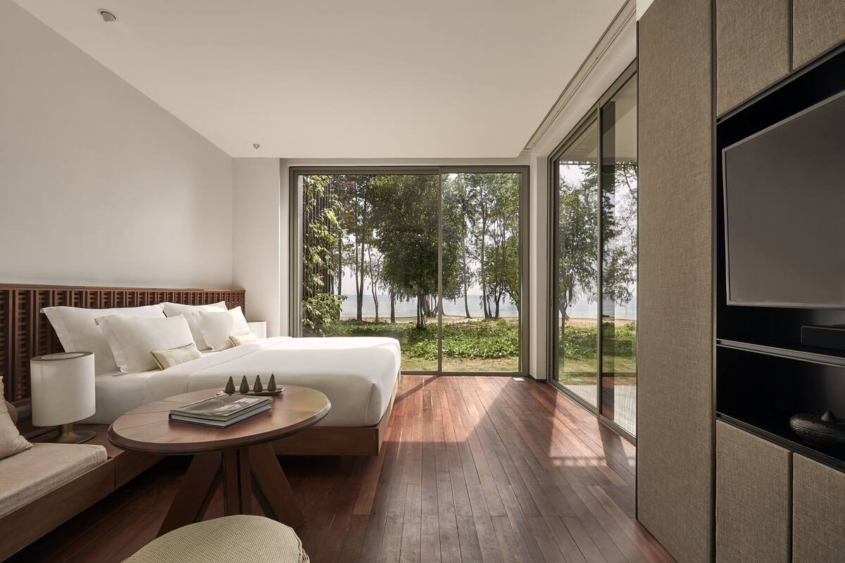 Une chambre moderne avec un grand lit, une télévision, un canapé et une vue sur un lac.