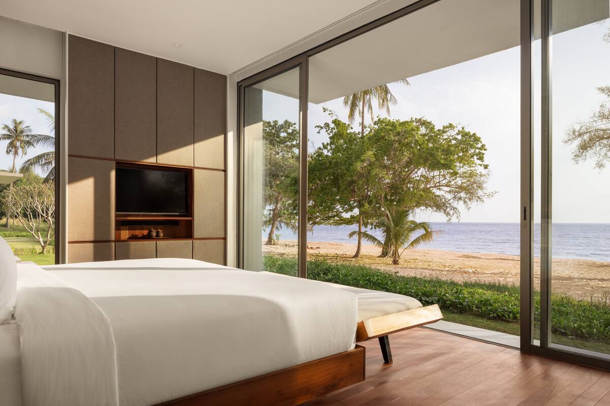 Une chambre avec un grand lit, une télévision et vue sur la plage.