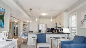 Een moderne keuken met witte kasten, een centraal eiland en hanglampen.