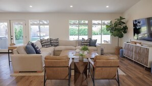 Una sala de estar moderna con un sofá seccional color beige, sillones de cuero y una mesa de centro de madera.