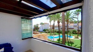 A room with a large window overlooking a swimming pool and palm trees. - 1176 Beachfront Paradise in Bahia de Marbella (Marbella)
