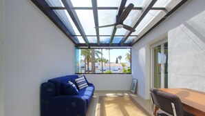 A sunlit room with a blue sofa, a wooden table, and a ceiling fan. - 1176 Beachfront Paradise in Bahia de Marbella (Marbella)