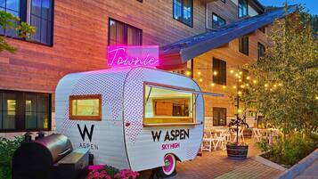 A food truck named "W ASPEN SKY HIGH" parked in front of a building with a neon sign "Tonnie" and string lights.