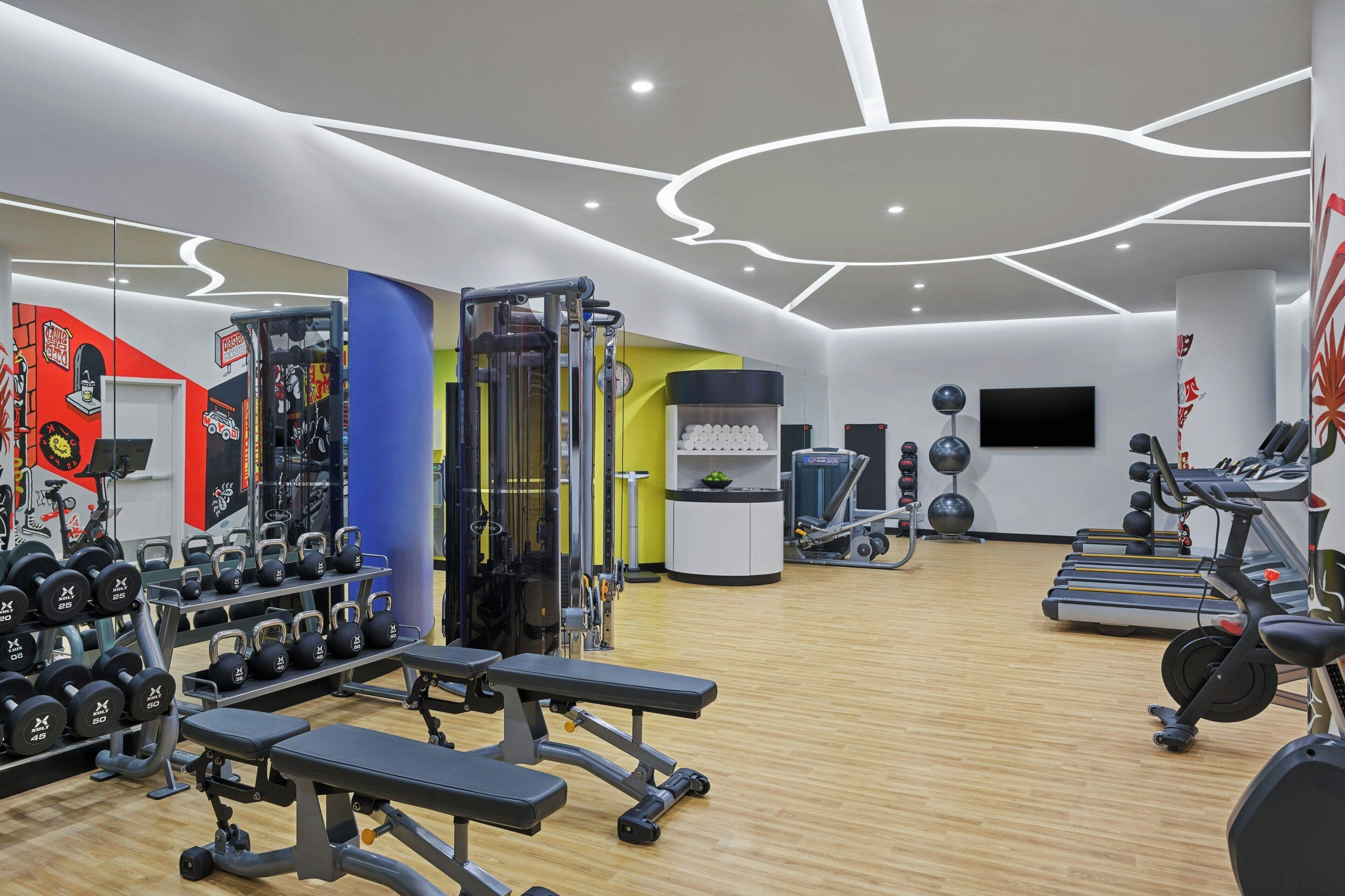 A modern gym with various exercise equipment, including treadmills, weight machines, and kettlebells.