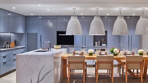 A modern kitchen with a marble island, wooden dining table, and pendant lighting. - The Sky Residences at W Aspen (Aspen)