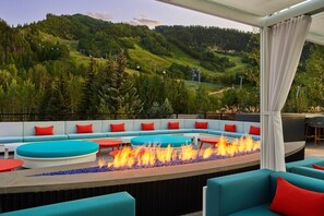 A modern outdoor seating area with a fire feature, overlooking a mountainous landscape. - The Sky Residences at W Aspen (Aspen)