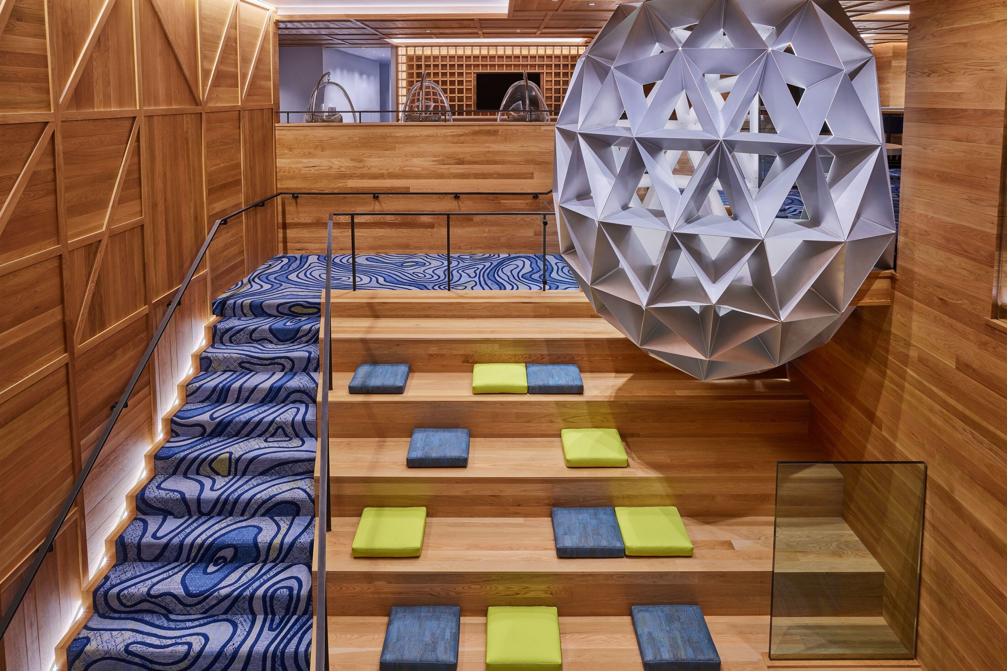 A modern interior with a wooden staircase, geometric wall panels, and a unique spherical structure.