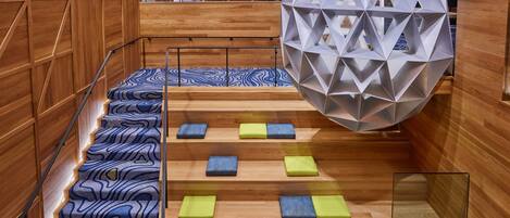 A modern interior with a wooden staircase, geometric wall panels, and a unique spherical structure.