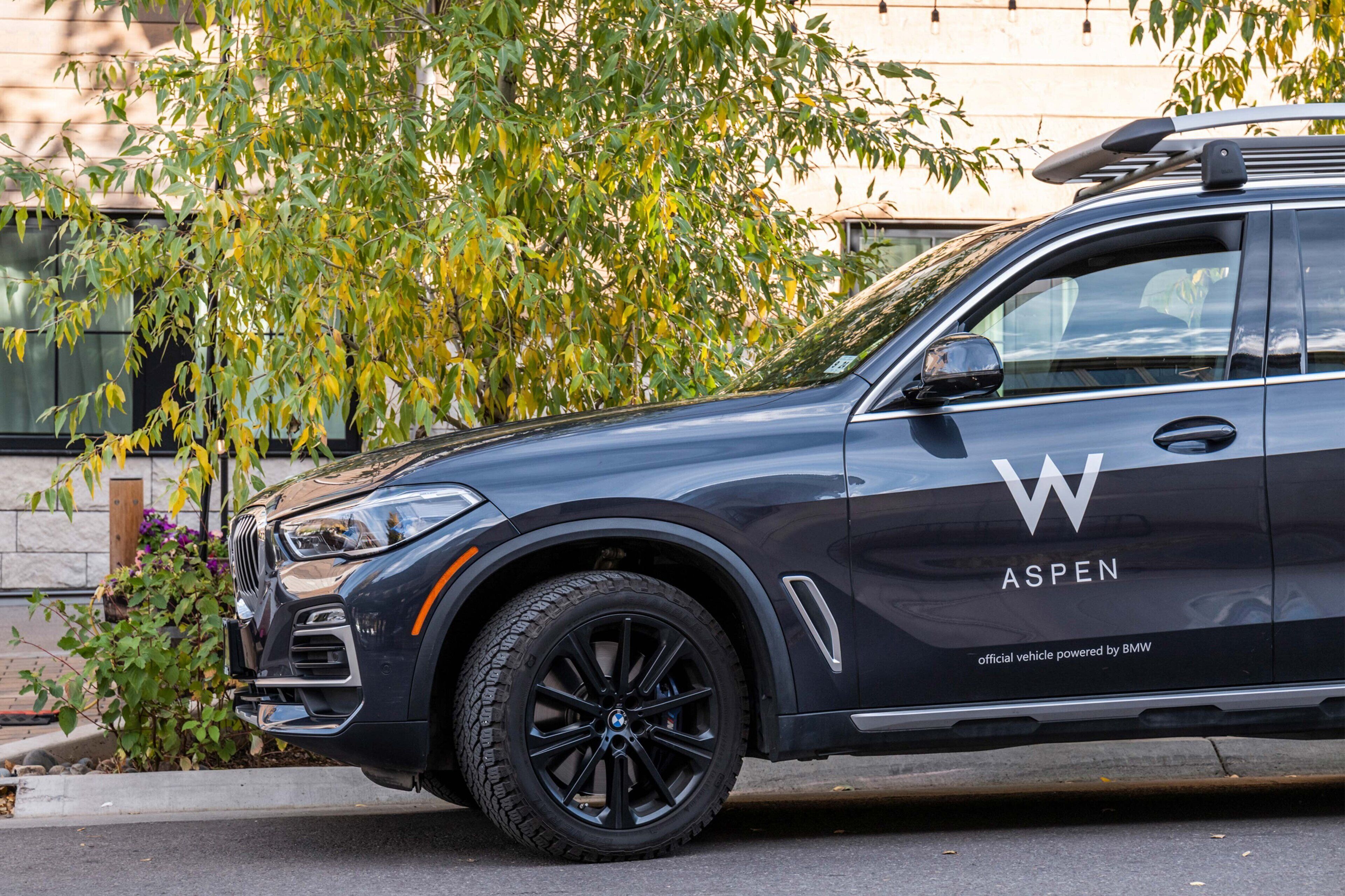 En svart SUV med logotypen ”ASPEN” och texten ”officiellt fordon, tillverkat av BMW  ” på sidan.