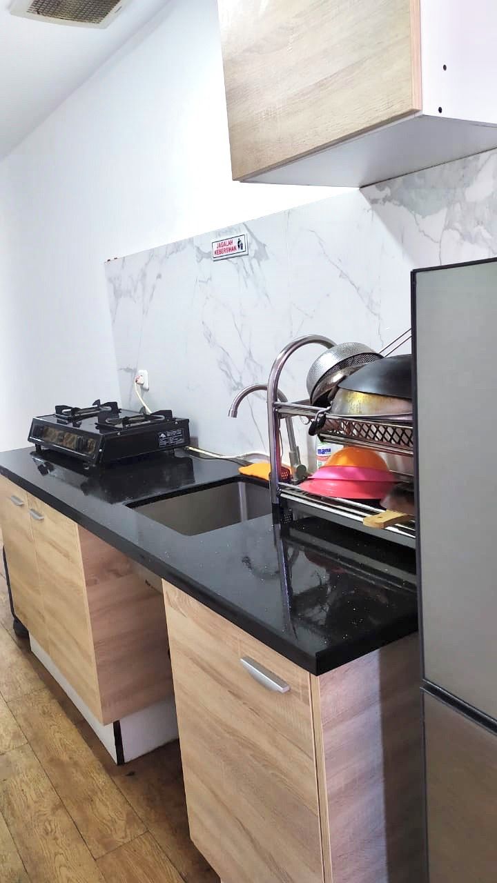 A kitchen with a black countertop, stainless steel appliances, and wooden cabinets.