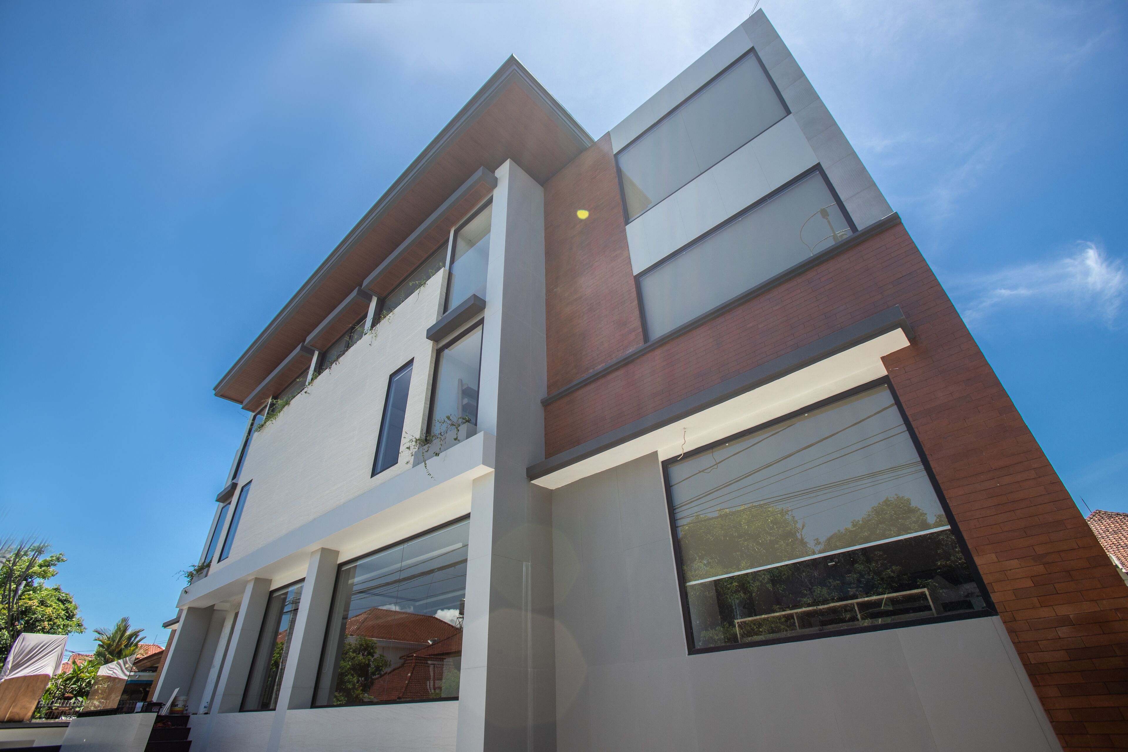 Un immeuble moderne à plusieurs étages, doté de grandes fenêtres et d’une façade combinant des éléments en brique et des murs blancs.