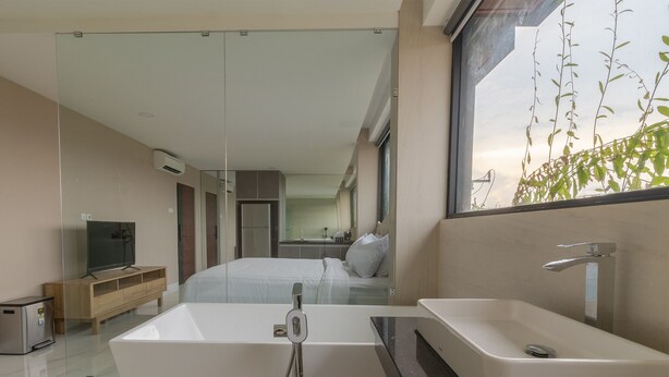 Un baño moderno con una bañera grande, un lavamanos independiente y una zona de ducha con paredes de vidrio.