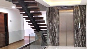 Un interior moderno con barandilla de vidrio, pared de mármol y ascensor.