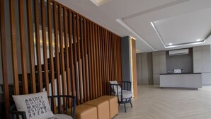 Un interior moderno con una recepción, un área de descanso con bancos acolchados y un separador de listones de madera.