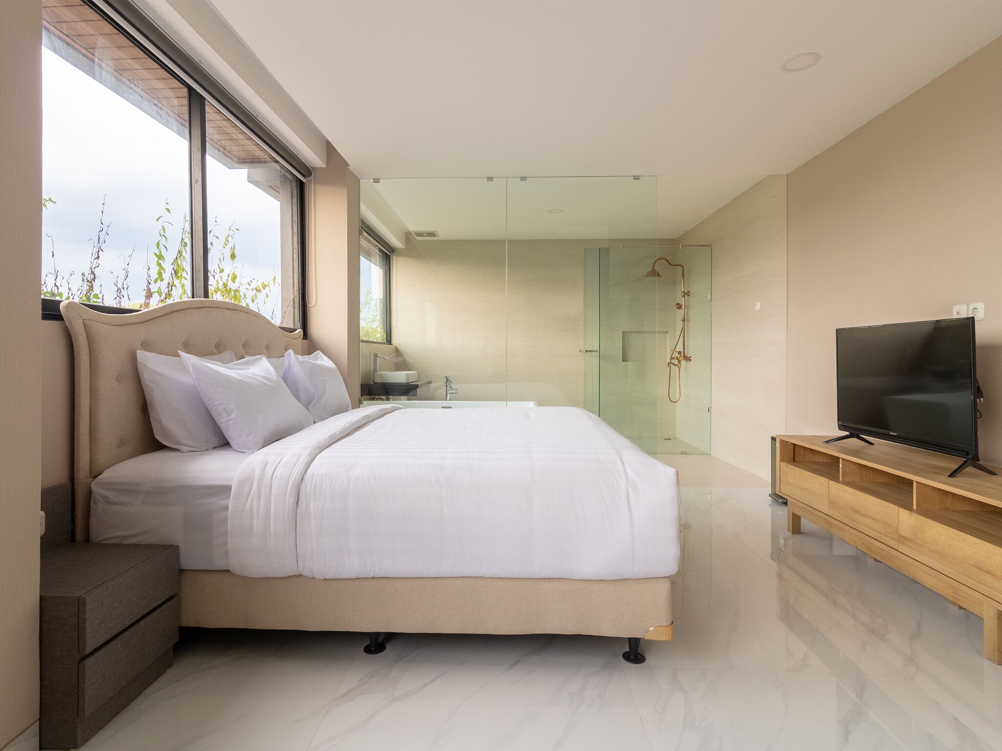 A modern bedroom with a large bed, a TV, and a glass-enclosed shower area.