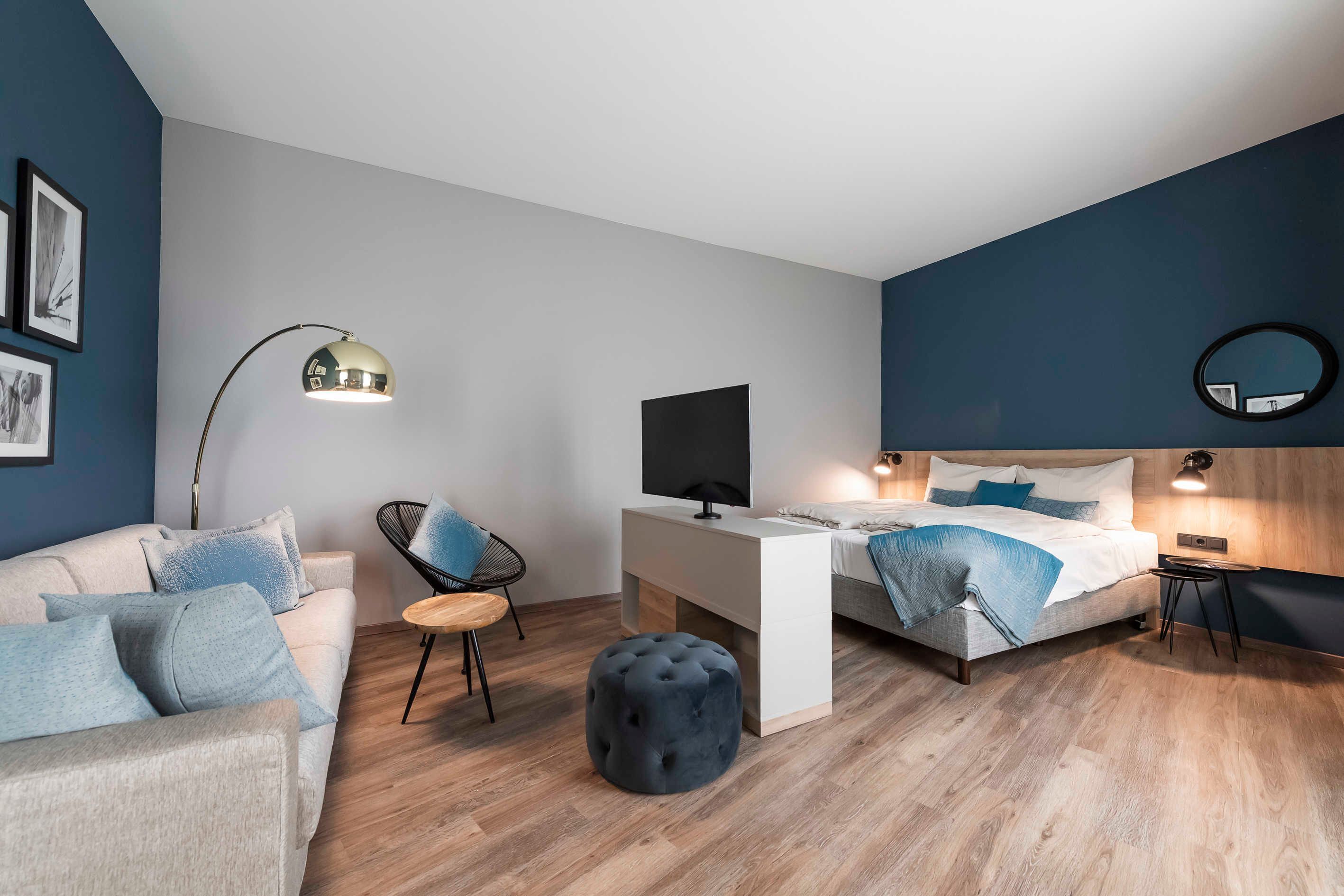 Une chambre moderne avec un lit, un bureau, une chaise et un miroir rond.