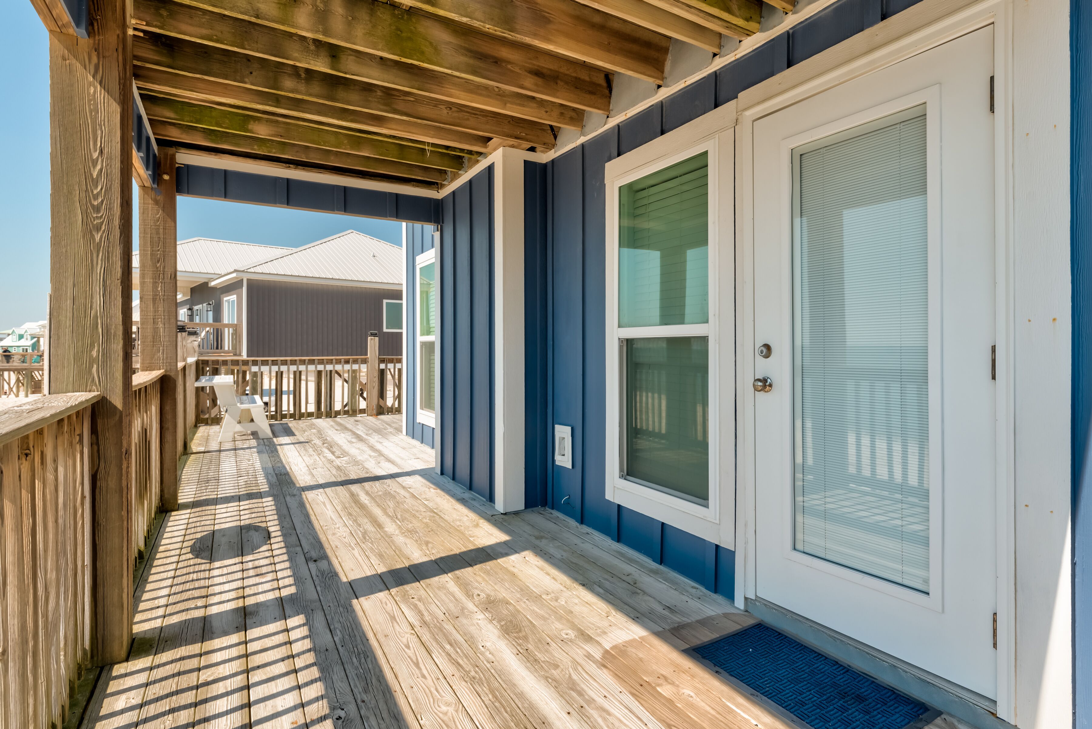 A wooden deck with a door and windows, leading to a covered porch area.