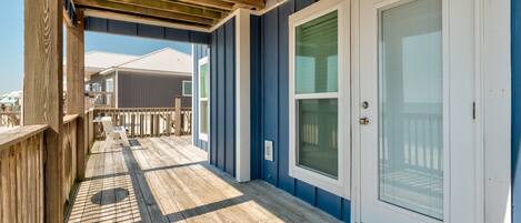 A wooden deck with a door and windows, leading to a covered porch area.