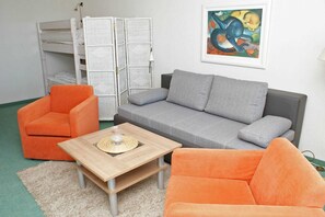 A room with a grey sofa, an orange armchair, and a wooden coffee table.