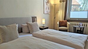 A hotel room with a bed, a chair, a table, a lamp, and a radiator. - Small double room - Altstadthotel Goldene Kugel Object ID 124185 (Waren (Müritz))