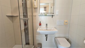 A modern bathroom with a glass-enclosed shower, a white sink, and a toilet. - Small double room - Altstadthotel Goldene Kugel Object ID 124185 (Waren (Müritz))