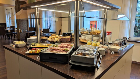 A buffet with various food items, including meats, cheeses, and fruits.