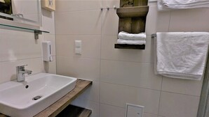 Ett badrum med handfat, spegel, handduksställ och en tvålbehållare.