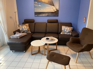En stue med sofa, to sofaborde, en lænestol og et billede på væggen.