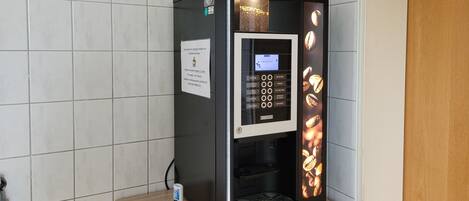 A coffee machine with a digital display, a coffee pod dispenser, and a coffee bean display.