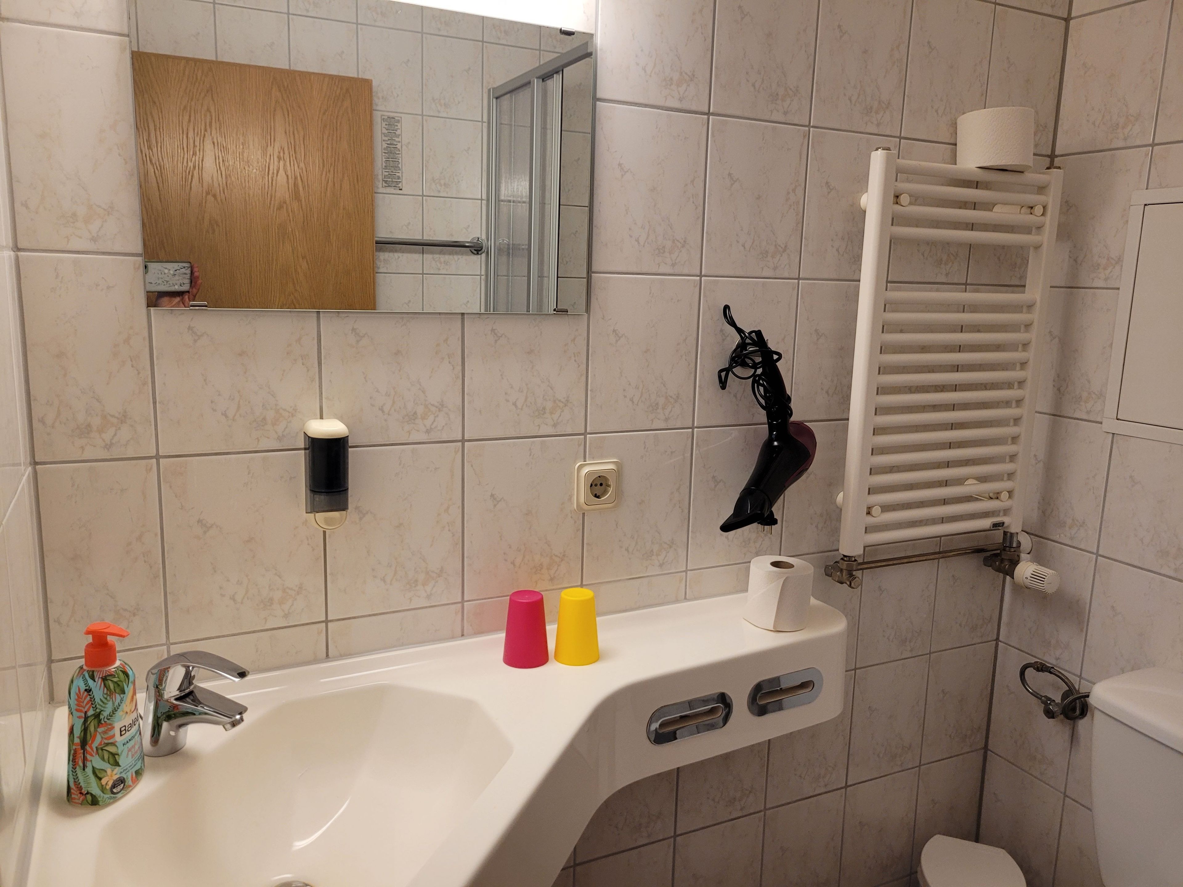 A bathroom with a sink, mirror, towel rack, and toilet.