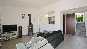 A modern living room with a flat-screen TV, a fireplace, a sofa, and a staircase leading to an outdoor area. - DJ's House - Modern and stylish villa by the sea in Mallorca (Son Serra de Marina)