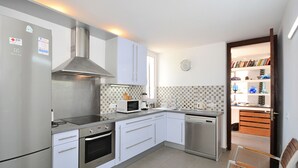 A modern kitchen with stainless steel appliances, white cabinetry, and a tiled backsplash. - DJ's House - Modern and stylish villa by the sea in Mallorca (Son Serra de Marina)