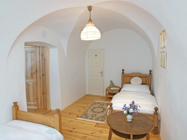 A bedroom with a wooden bed, a bedside table with a vase of flowers, and a wooden floor. - Apartmány Domestika (Cesky Krumlov)