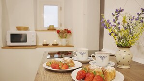 Una mesa de madera con pasteles, fresas, una taza y un florero.