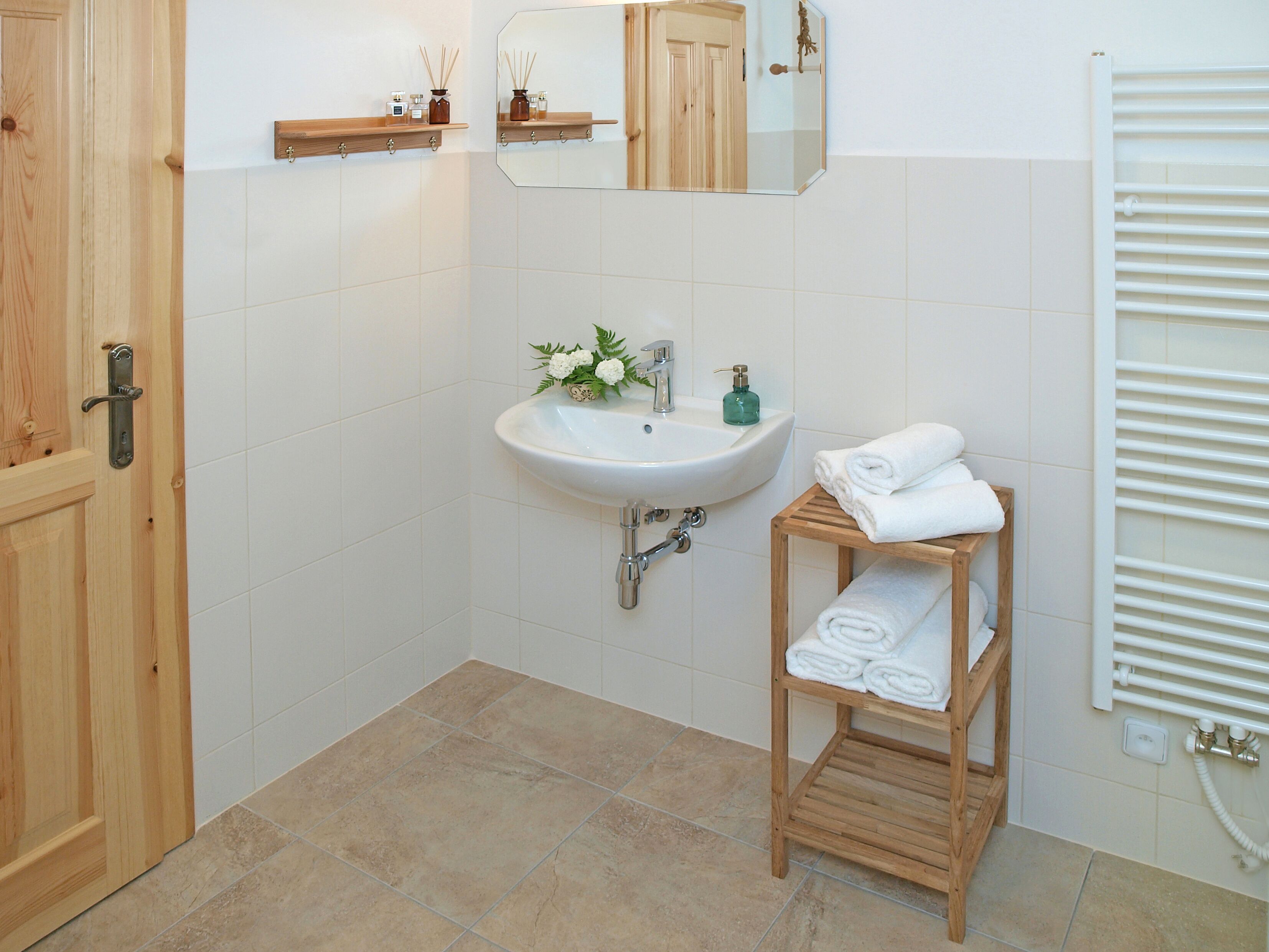Een badkamer met een wit wastafelmeubel, houten planken en een spiegel.