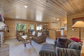 A log cabin interior with a living area, sofa, coffee table, and a kitchen area.