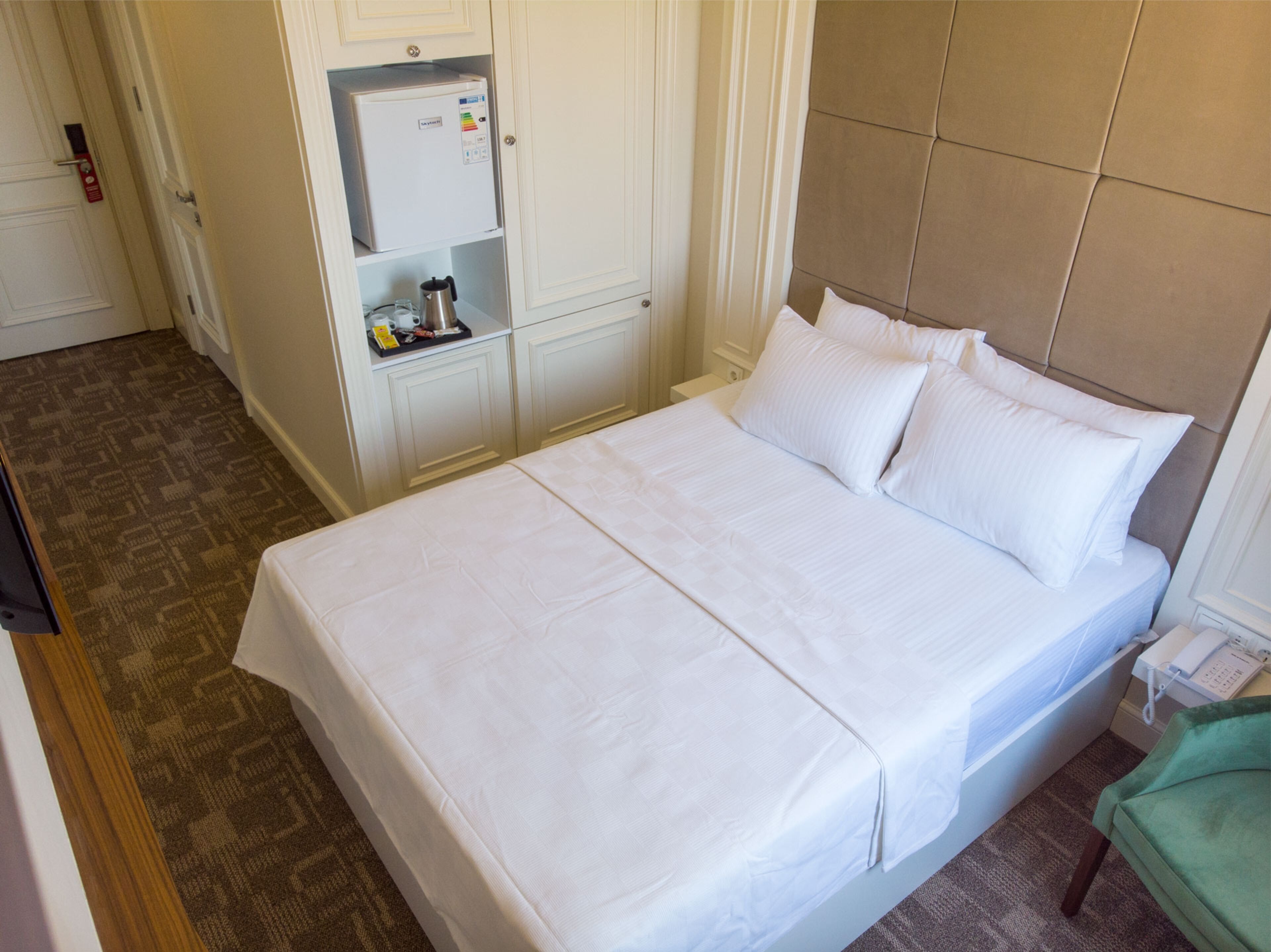 Una habitación de hotel con cama, minibar y puerta.