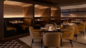 A restaurant with booths and tables, each with candles and glasses. - Kimpton Cottonwood by IHG (Omaha)