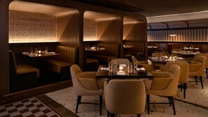 A restaurant with booths and tables, each with candles and glasses. - Kimpton Cottonwood by IHG (Omaha)