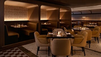 Un restaurant avec des banquettes et des tables, chacune agrémentée de bougies et de verres.