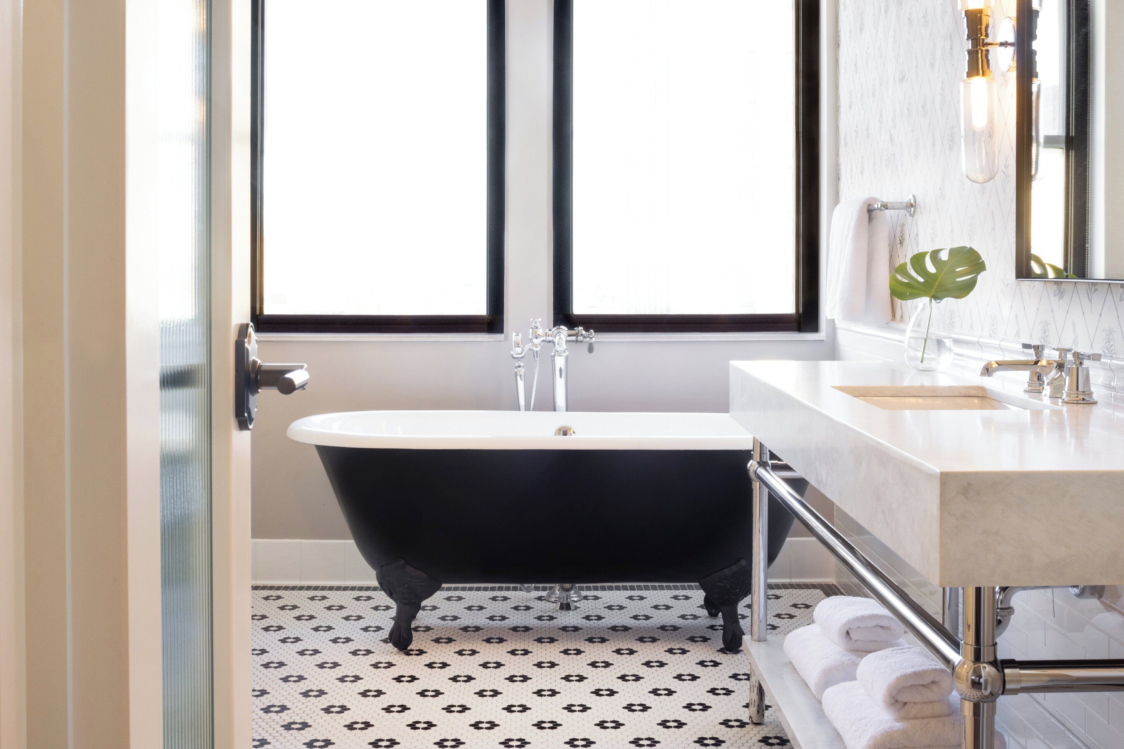 A bathroom with a black clawfoot bathtub, a white sink, and a large mirror.