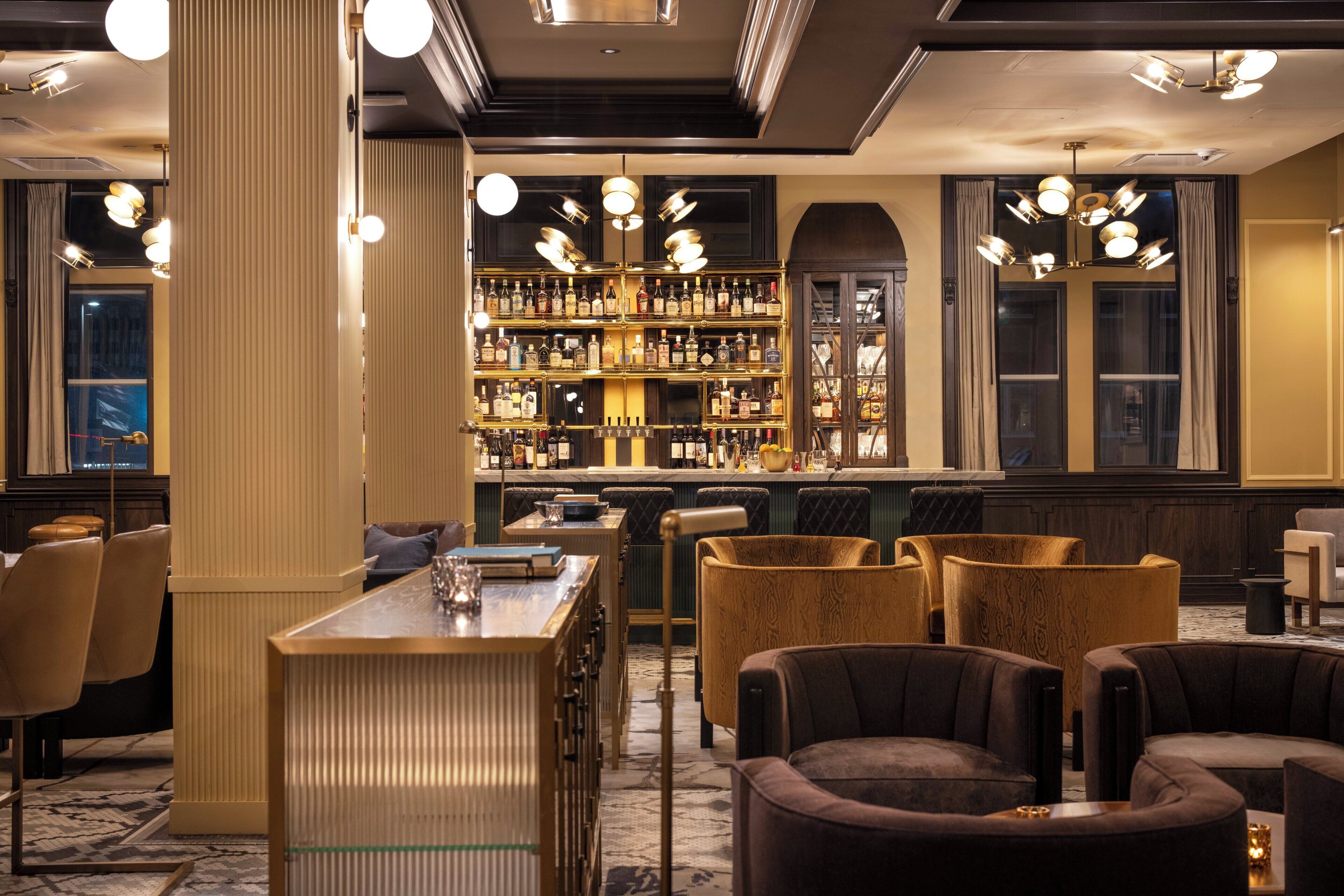 A bar area with a wooden bar counter and multiple seating options including sofas and armchairs.