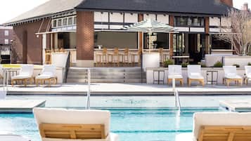 Zona junto a la piscina con sillones de descanso y un bar.