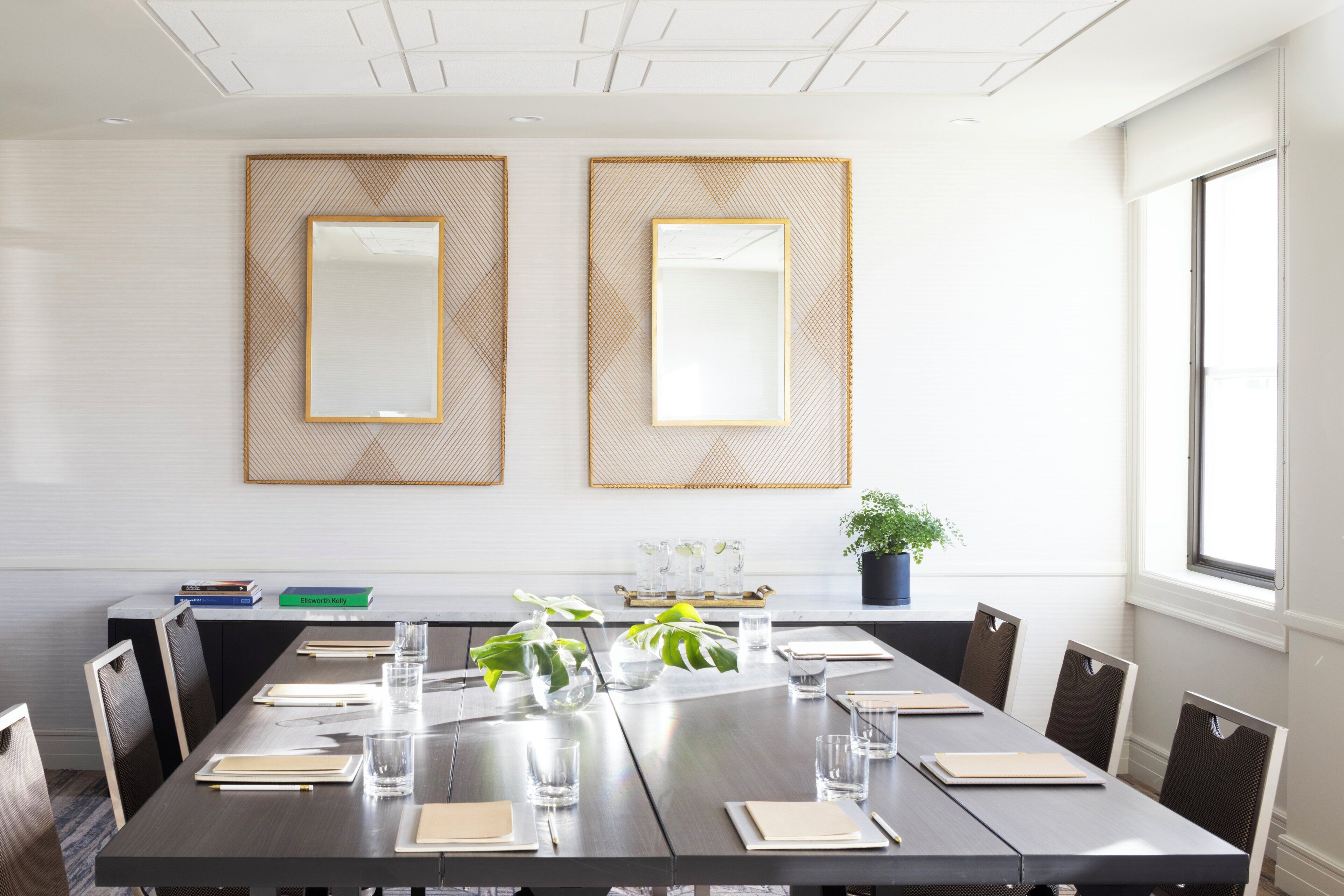 A conference room with a long table, chairs, and a potted plant.