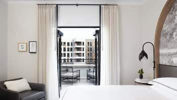 Une chambre d’hôtel avec un lit, une chaise, un bureau et une vue sur les bâtiments environnants.