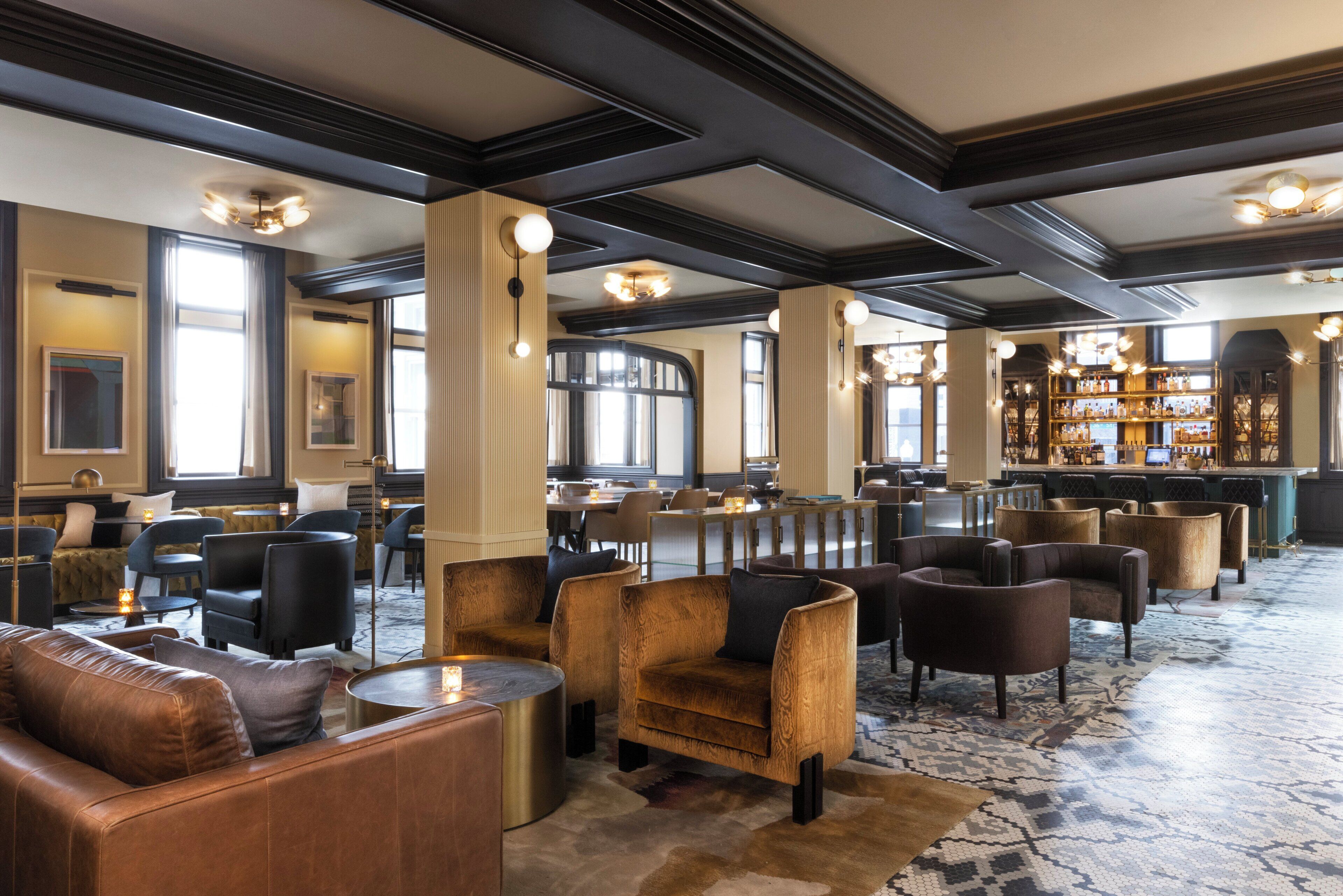 A spacious lobby with multiple seating areas, a bar, and a view of the city.