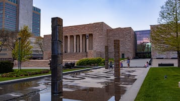 Un patio con un edificio de piedra, una fuente y un elemento acuático reflectante.