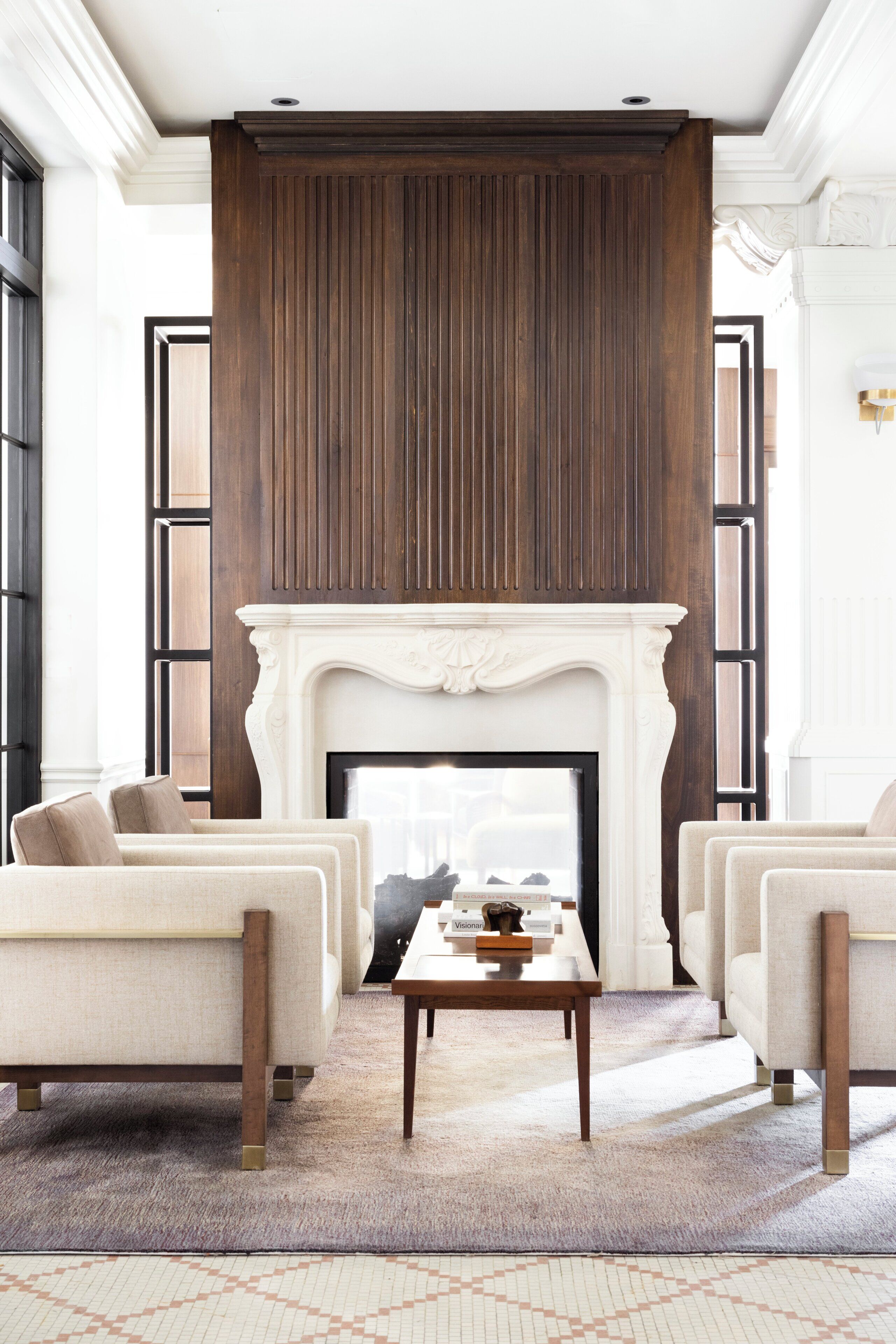 A room with a fireplace, two armchairs, a coffee table, and a patterned carpet.