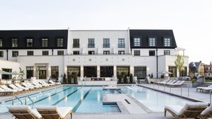 A modern hotel with a large outdoor swimming pool, sun loungers, and a well-maintained garden area. - Kimpton Cottonwood by IHG (Omaha)